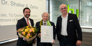 Group photo: The professors Strese, Zahra, and Bayer. In the background: a projection screen and a window front.