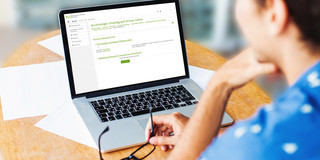 Frau am Laptop Eine Frau schaut auf ihren geöffneten Laptop.