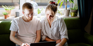Studierende arbeiten digital Zwei Studierende arbeiten am Laptop, auf einem Sofa sitzend.