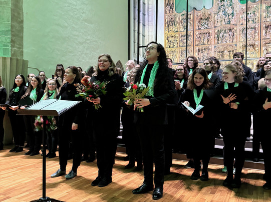 Der Unichor vor dem Altar der St.Petri Kirche. Vorne stehen Heinke Kirzinger und Felix Köhler. 