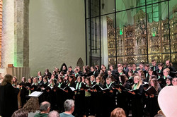 Der Unichor vor dem Altar in der Petri-Kirche. Vorne links steht die Chorleiterin Heinke Kirzinger.