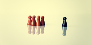 Eine Gruppe von 6 roten Spielfiguren, daneben eine einzelne schwarze Spielfigur