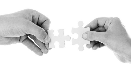 Hände, die ein Puzzleteil verbinden
