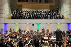 Blick auf Solist und Solistin mit Orchester im Hintergrund. Der Chor steht auf der Empore vor der Orgel.